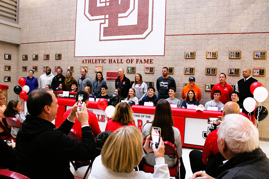 12 student-athletes pose for photo with coaches on national signing day.