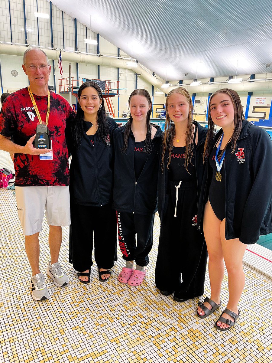 Swim team members pose for group photo near pool.