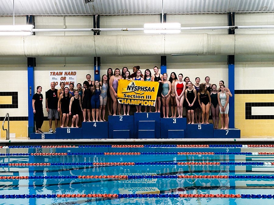 J-D swim poses for championship photo next to pool.
