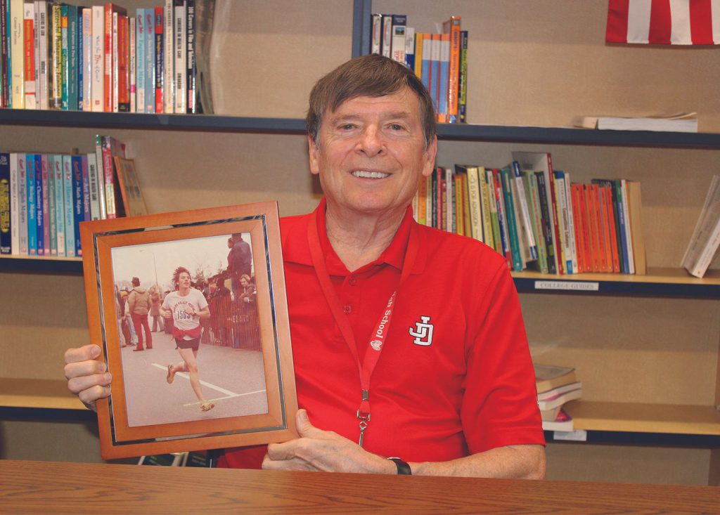 Jim Lawton holds a photo of himself taken in 1978 when he ran his first marathon.