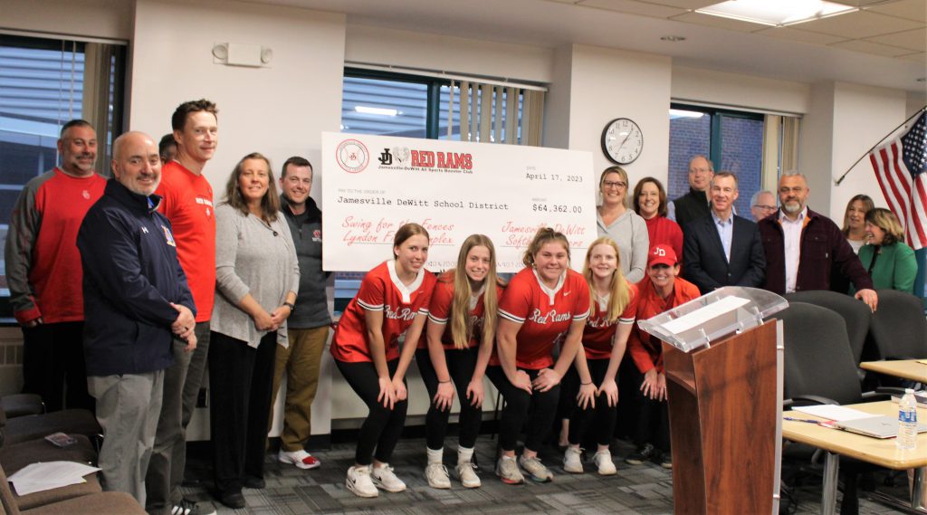 Image of group photo including Varsity Softball players, board of education members, and school administration with large check. 
