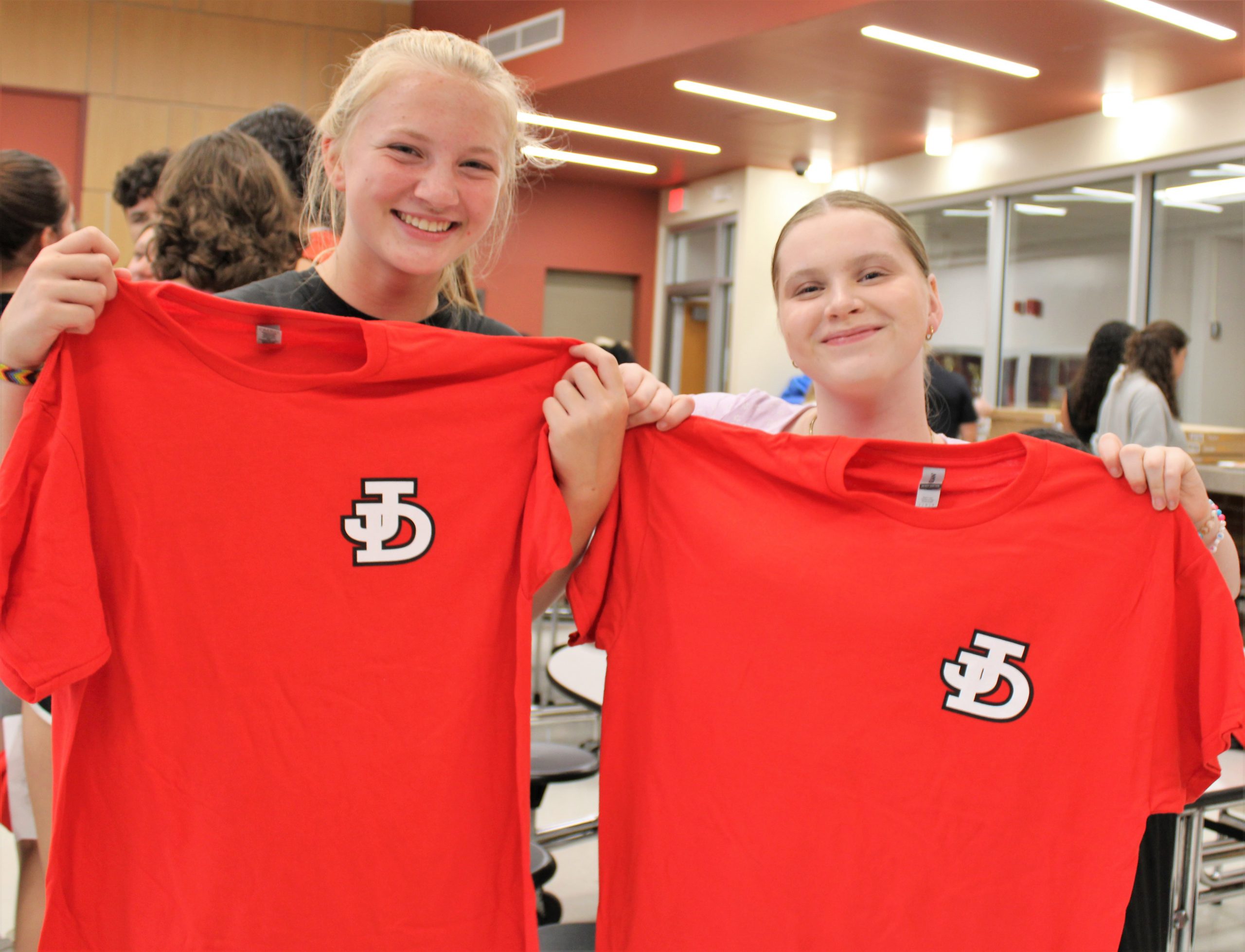 Photo of two students holding red J-D shirts.