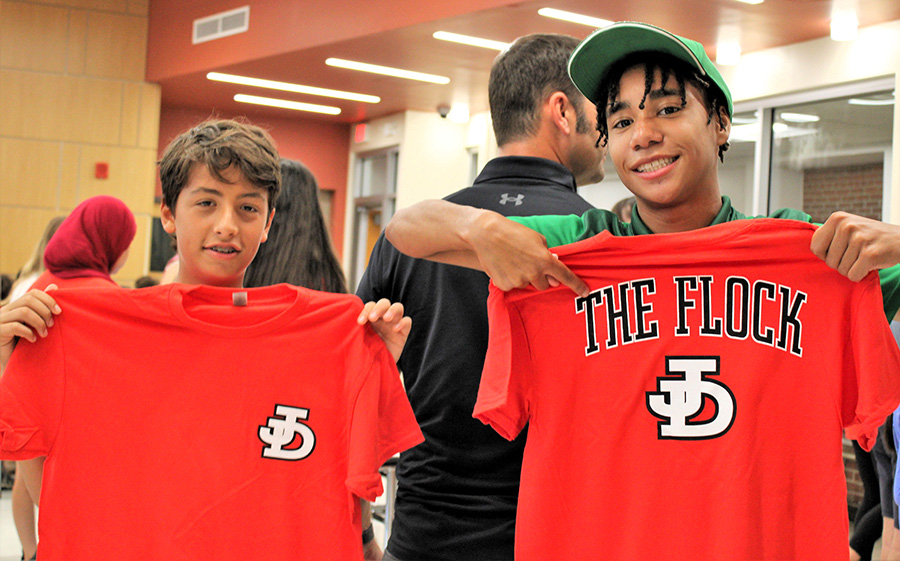 Image of two students holding up J-D shirts