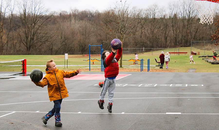 Image of two students playing basketball outside.