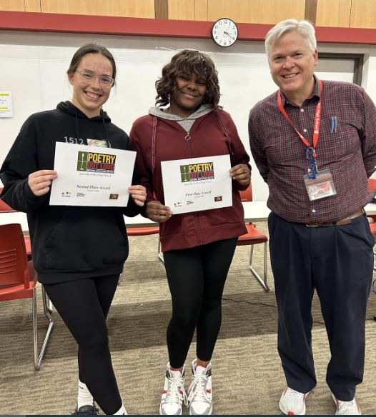 Image of two students standing with teacher. 