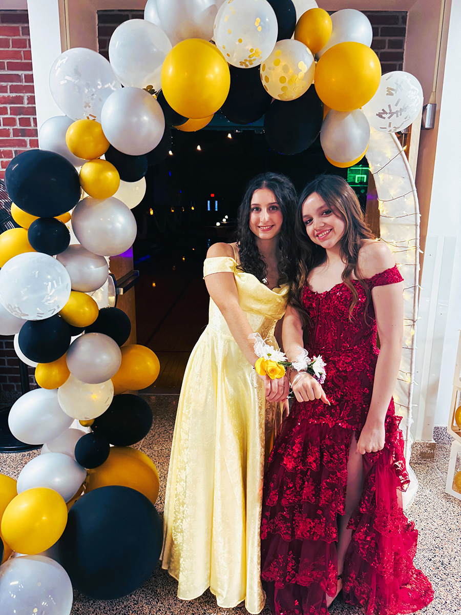 Junior students pose for prom photo in front of balloon arch.
