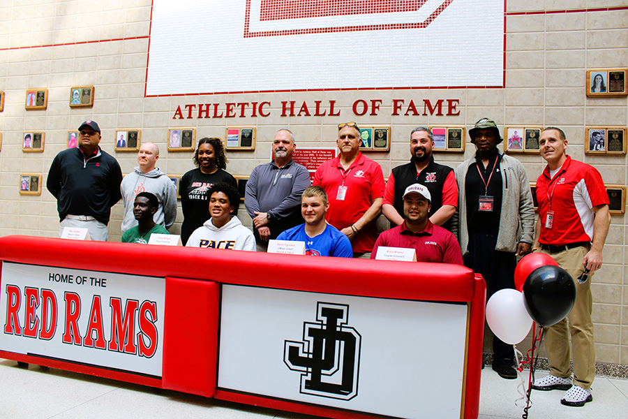 Four student-athletes pose for group photo with coaches for national letter of intent signing.