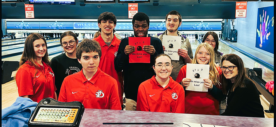 2025 Unified Bowling team smiles with signs.