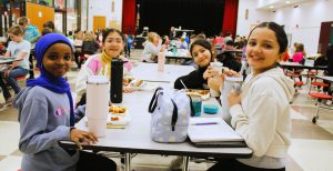 students sitting at a cafeteria table eating lunch