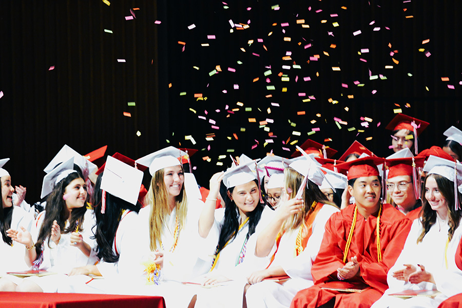 Class of 2025 seniors smile as confetti falls during graduation.