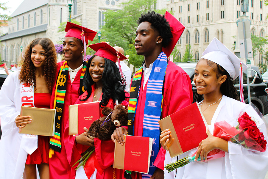 Five graduates pose for photo with diplomas.
