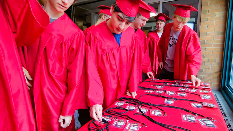 Seniors wearing red caps and gowns find name badge.