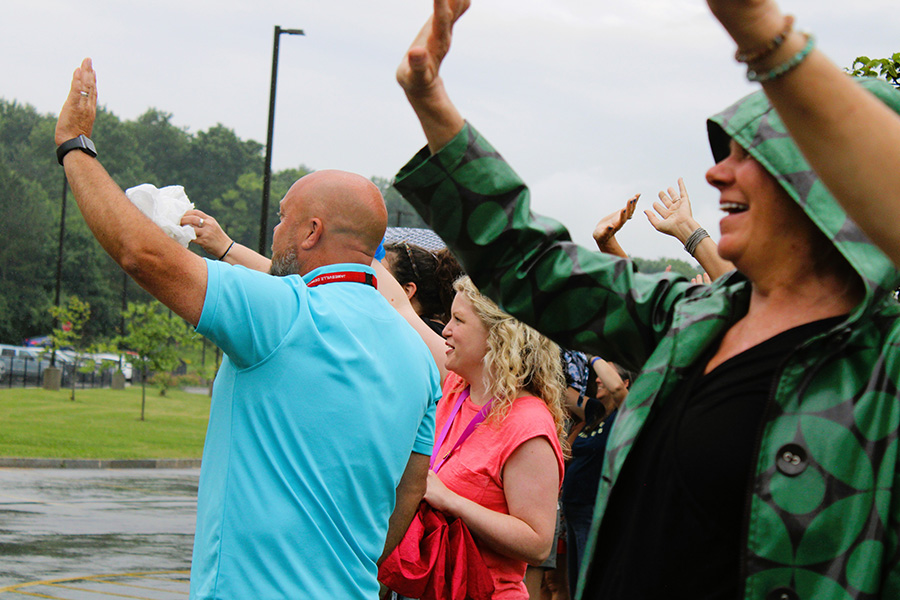 Staff wave to students leaving school on buses.