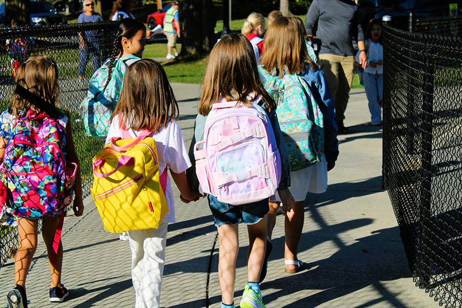A group of elementary students walk together into school.