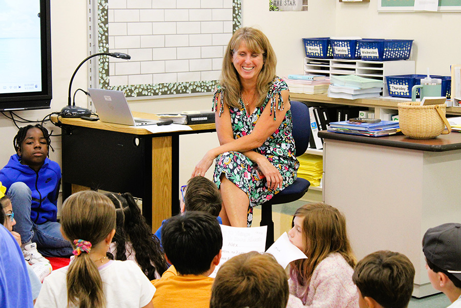 Tecumseh teacher smiles at students gathered around her.