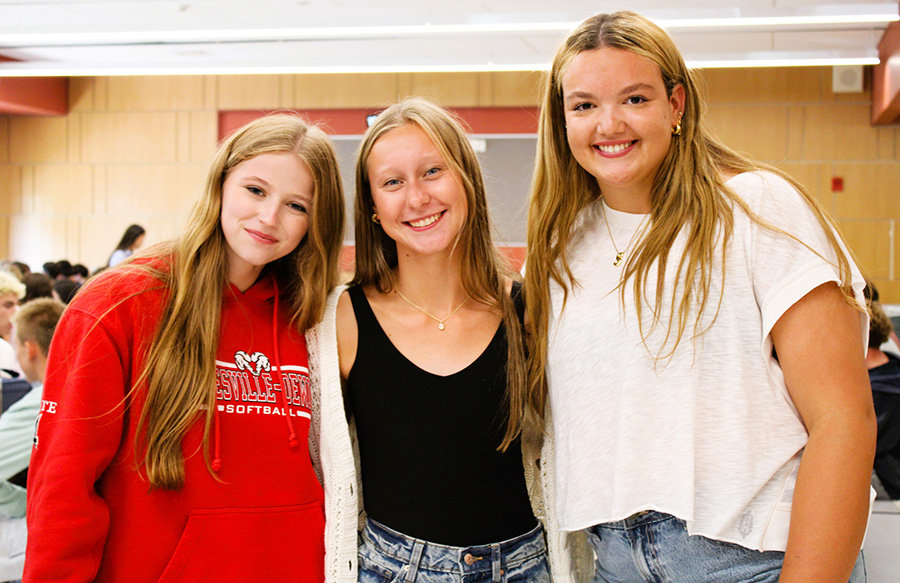Three students smile for photo in cafeteria.