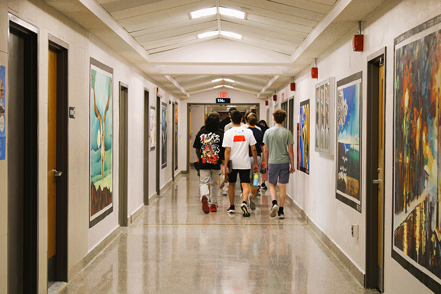 Group of students walk down hallway.