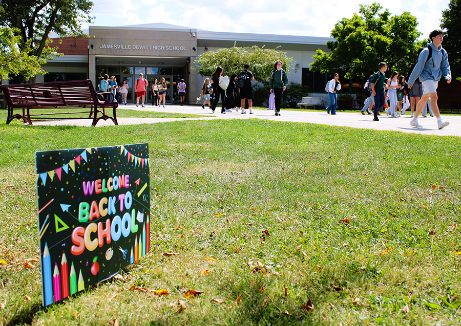 Students leave school building with welcome back sign in the foreground.