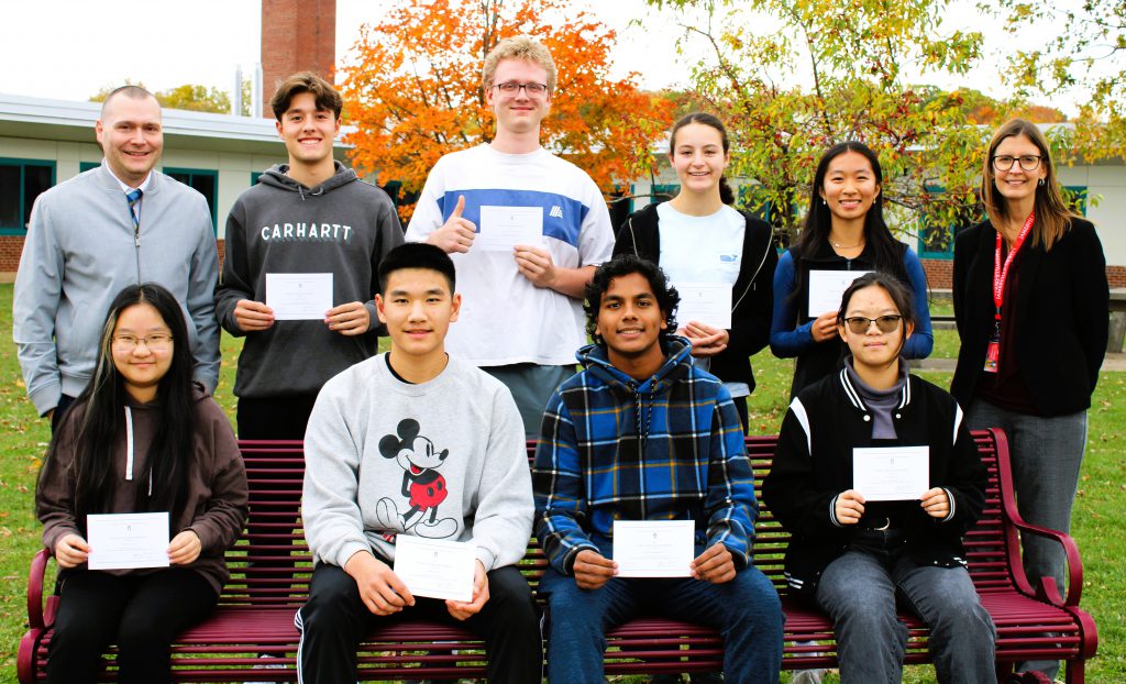 Lauren Caporaso, Nicole Chen, Daniel Luo, Flora Mei, Daniel Nemi, Rehaan Rakhesh, Emma Ralph, Oscar Williamson, and Olivia Yang pose for group photo with Superintendent Darcy Woodcock and Principal Gregory Lawson.
