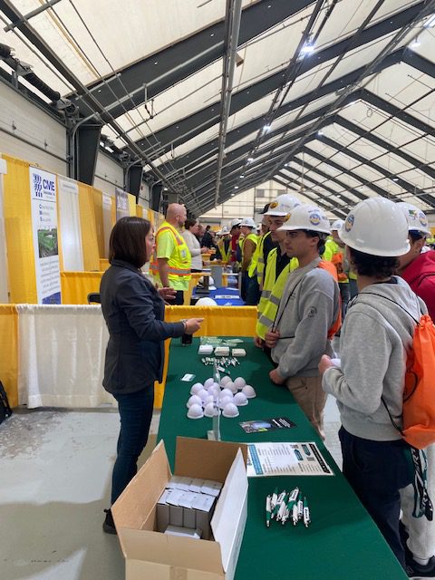 Students speak with representative at construction booth.