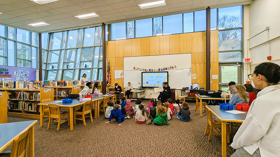 High school student reads to Tecumseh students in the library.