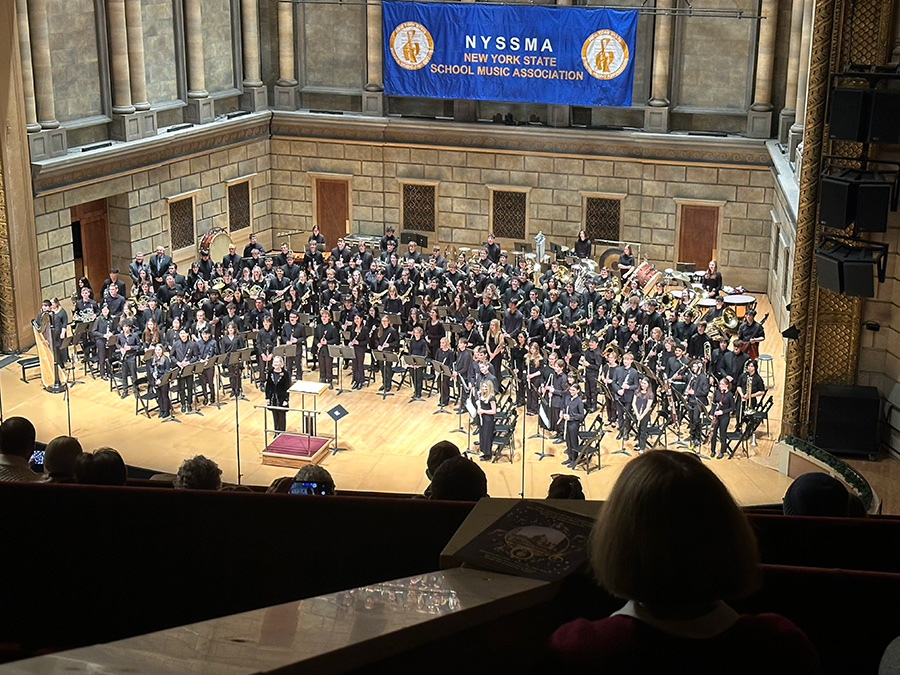 Student musicians perform on large theater stage.