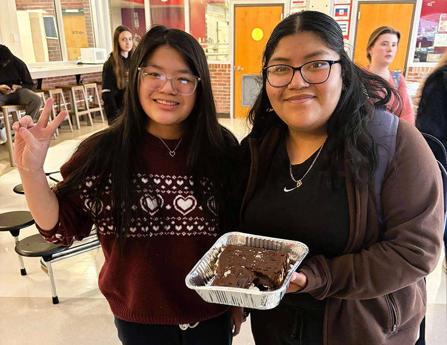 Two students hold festive cake they made for French Club.