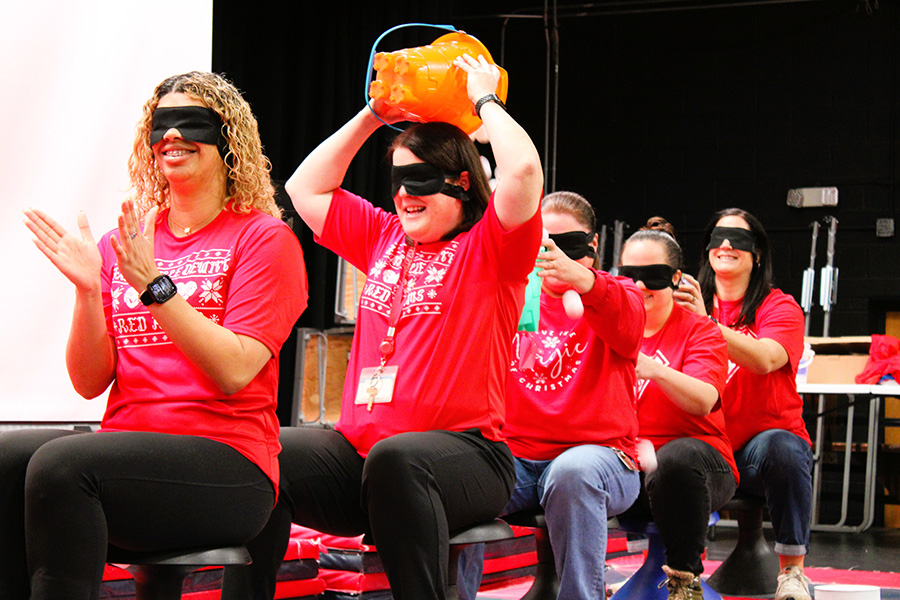 Staff sit in a line wearing blindfolds playing winter game with ping pong balls.
