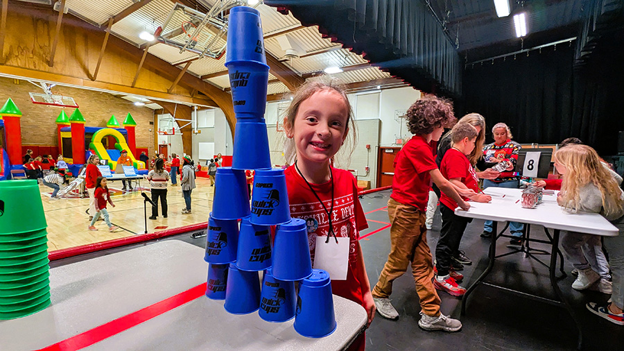 Student smiles near stacked cups.