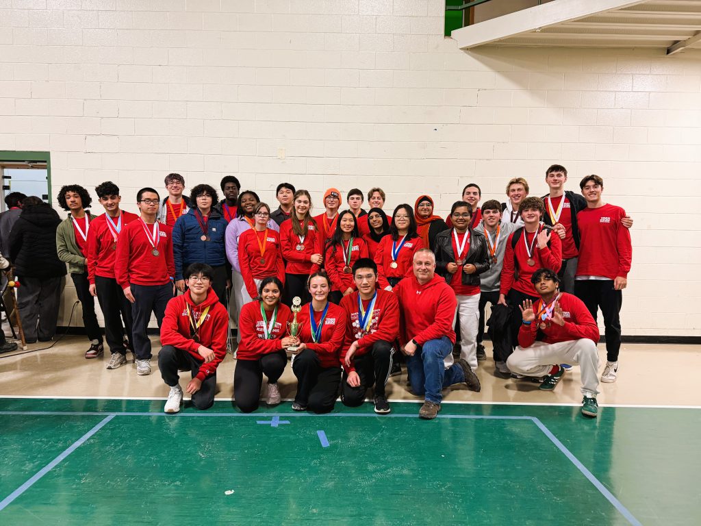 J-D High School students pose for group photo wearing matching red shirts with trophy.