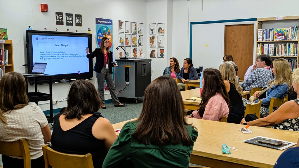 Superintendent Woodcock presents on smartboard in front of staff.