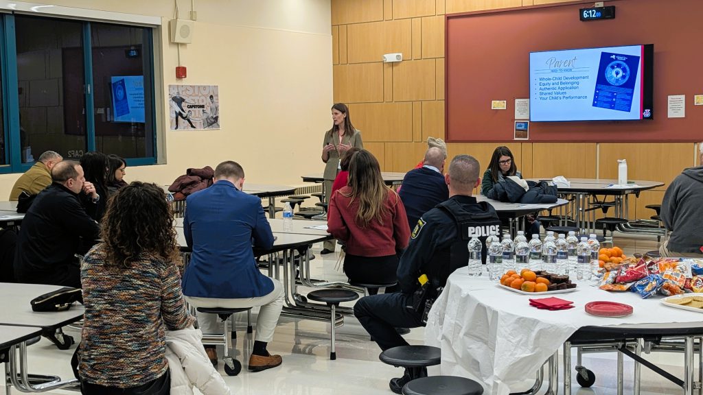 Superintendent Woodcock speaks in front of forum audience in cafeteria.