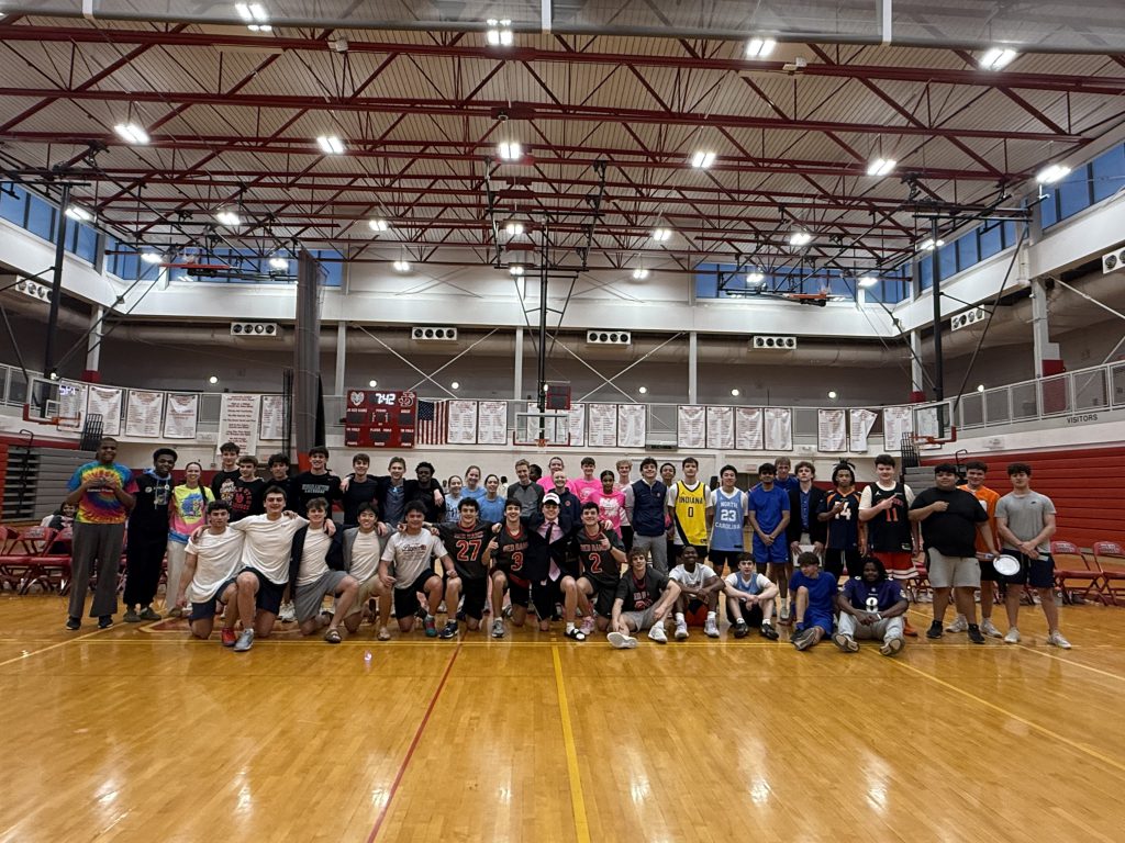 Students participating in 3 on 3 basketball tournament pose for group photo in gym.