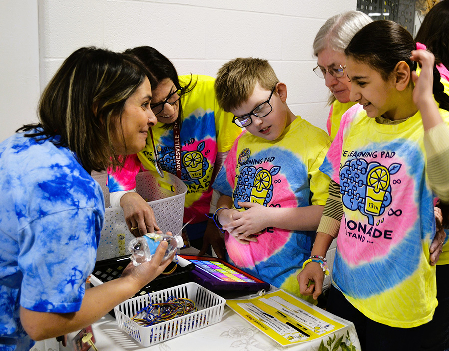 Students and staff wear colorful tie dye shirts and sell lemonade to a teacher.