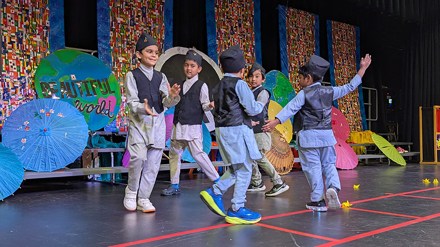 A group of male students dance in a circle wearing their cultures clothing.