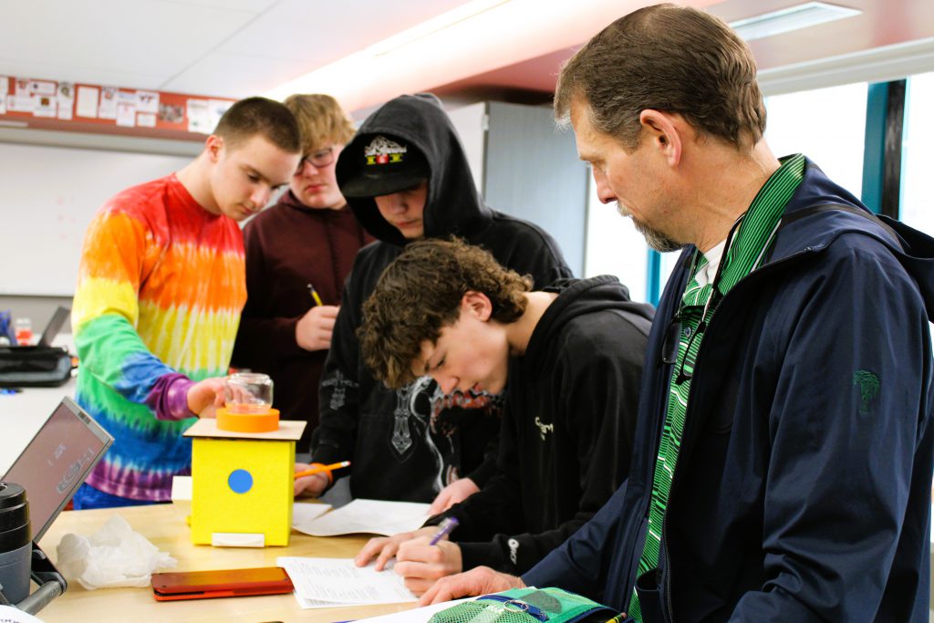 Several students test out candy dispensing machine with teacher.