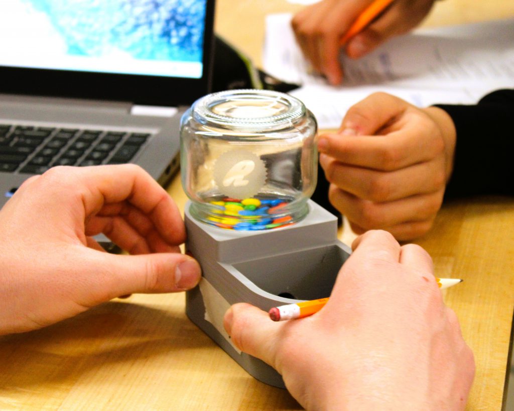 Students test out 3D printed candy dispenser shaped like a toilet.