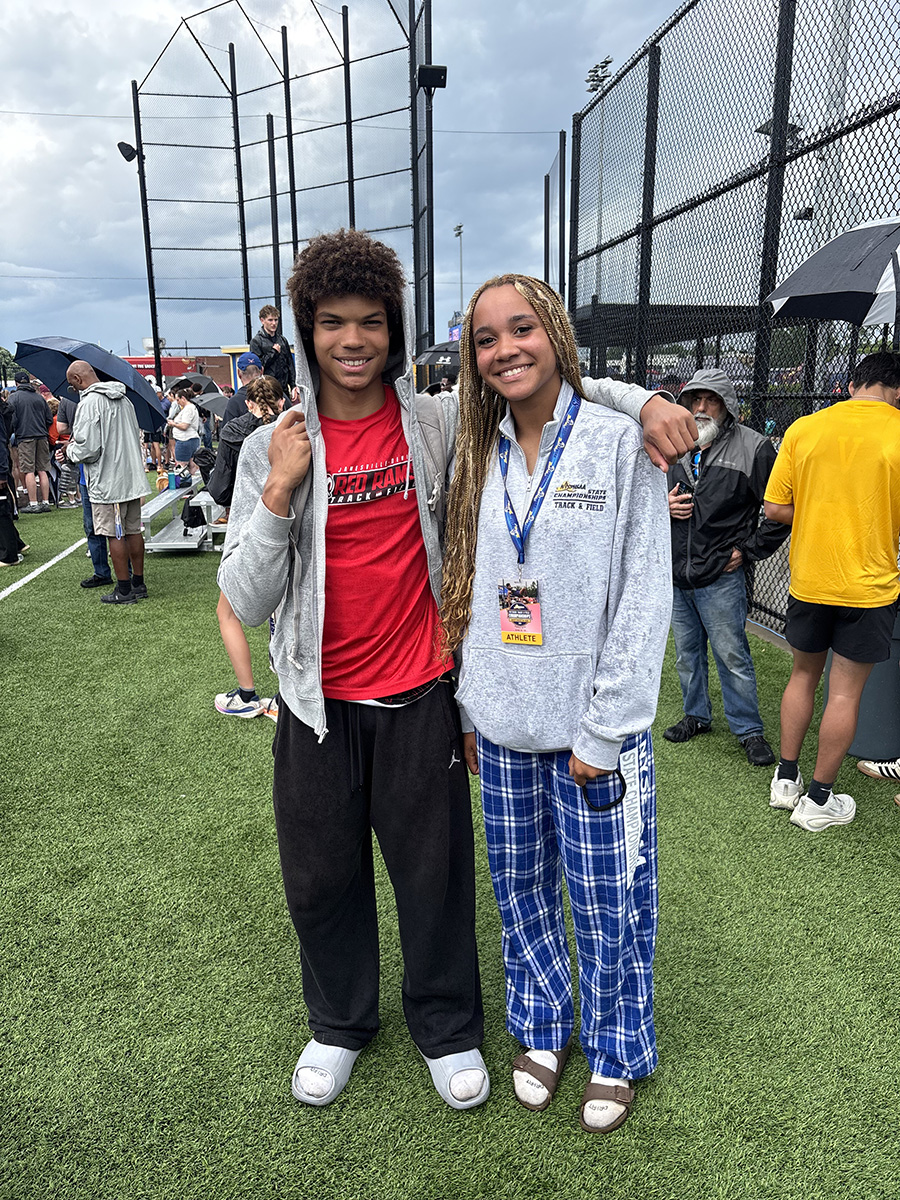 Two students pose for photo outside wearing medals.