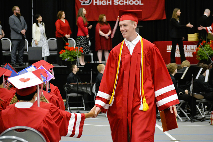 Graduate shakes hand while walking back to seat.