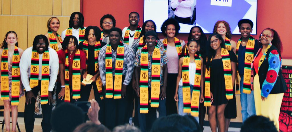 Large group of seniors take group photo wearing Kente stoles.