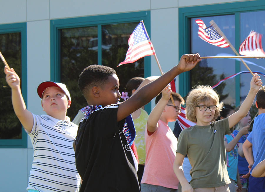 Students wave American flags outside.
