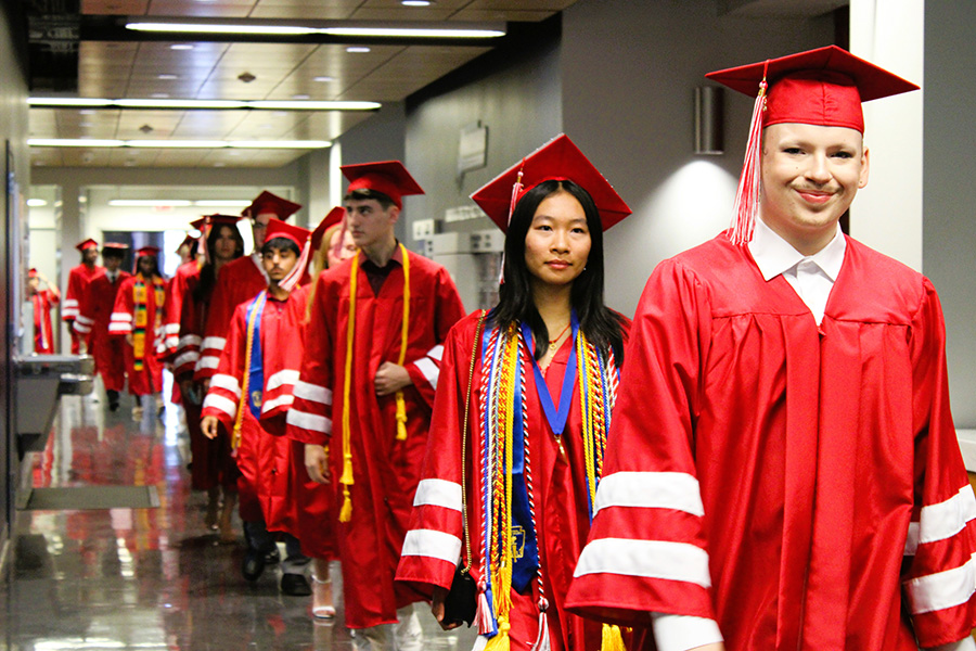 Graduates walk down hallway.