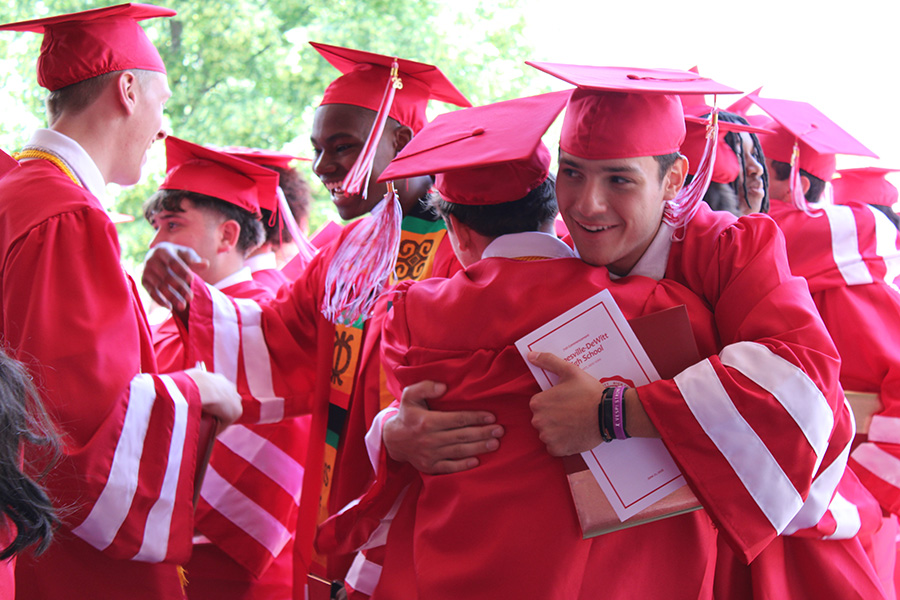 Graduates hugging in caps and gowns.