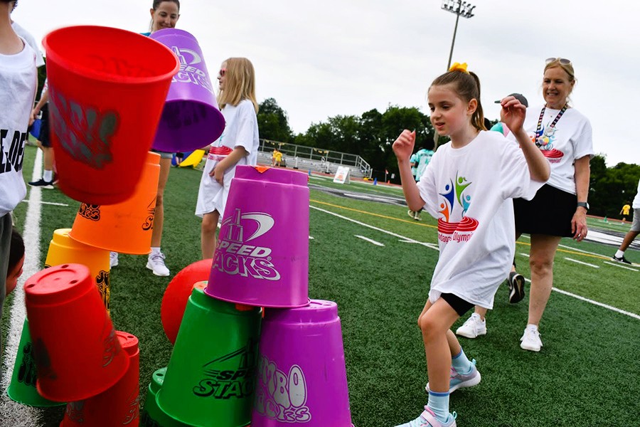 Student throws ball at stacked cups.