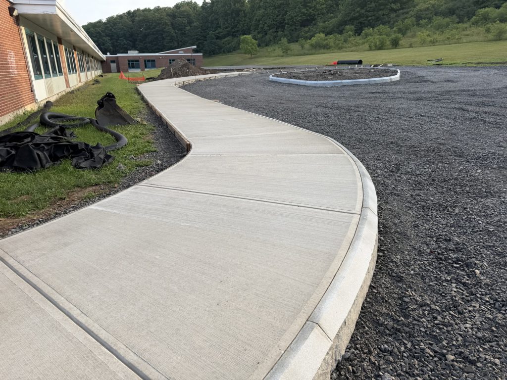 Parking lot construction showing new sidewalks and gravel.