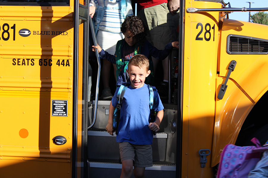 Student smiles while getting off bus.