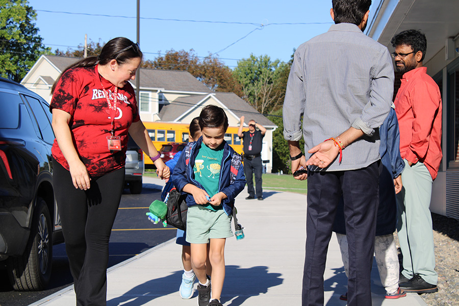 Staff walks students towards building.