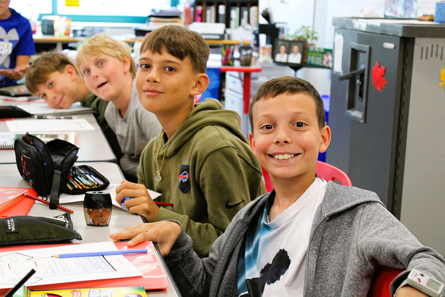 Students smile toward camera at desks.
