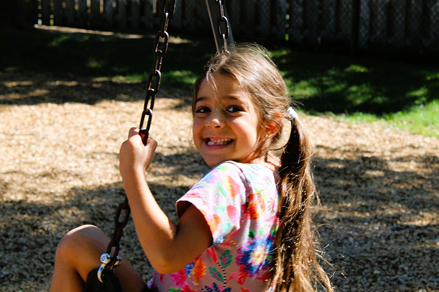 Student smiles on swing.