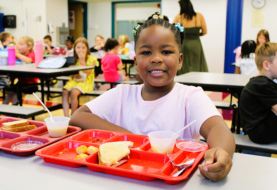 Student smiles with lunch tray.